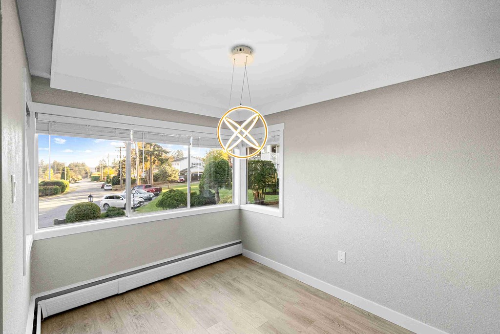 an empty living room with a large window and a chandelier