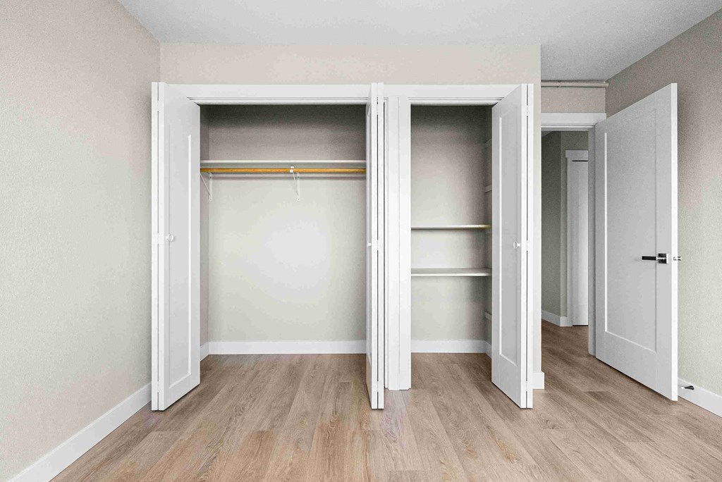 an empty room with a closet with doors open