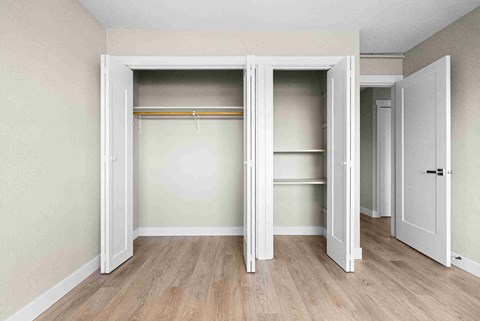an empty room with a closet with doors open