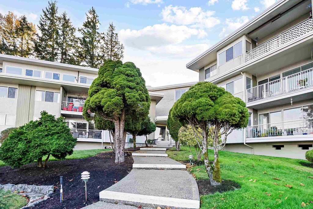 an exterior view of an apartment building with trees and pathways