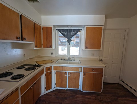 an empty kitchen with wooden cabinets and a window