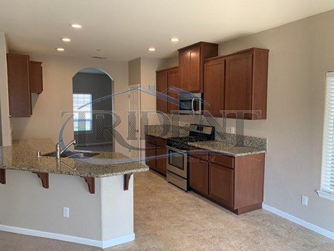 A kitchen with brown cabinets and granite countertops.