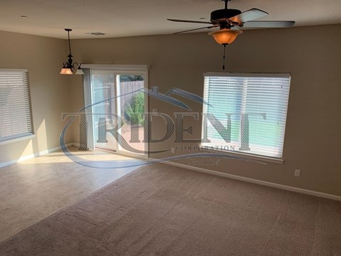 A room with a carpeted floor, a ceiling fan, and a window with blinds.