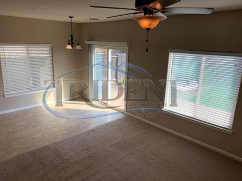 A room with a fan, carpet, and a window with blinds.
