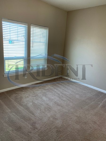 A room with a carpeted floor and a window with blinds.