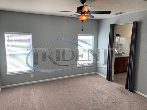 A room with a carpeted floor and a ceiling fan with a light.