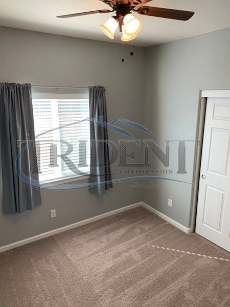 A room with a ceiling fan and a window with curtains.