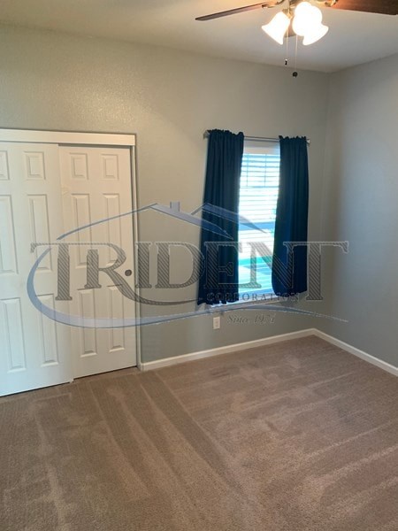 A room with a carpeted floor and a ceiling fan.