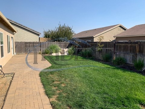 A backyard with a brick walkway and a wooden fence.