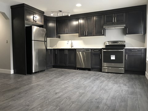 an empty kitchen with black cabinets and stainless steel appliances