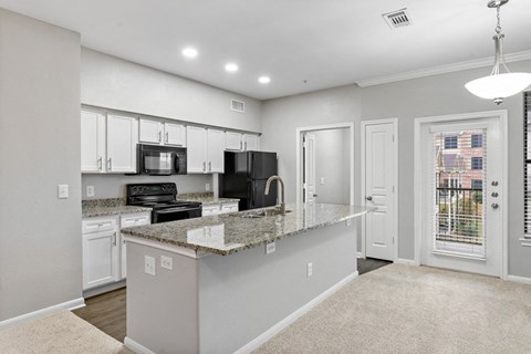 an open kitchen with granite counter tops and white cabinets