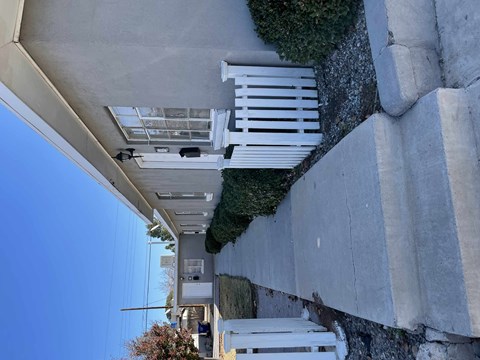 A white structure with a glass roof is attached to a concrete wall.