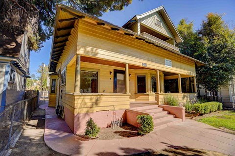 the front of a yellow house with a porch and stairs