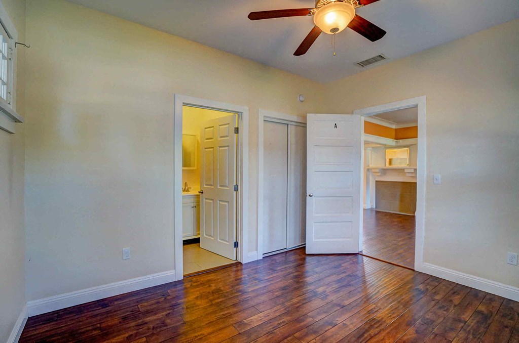 an empty living room with wood floors and a ceiling fan