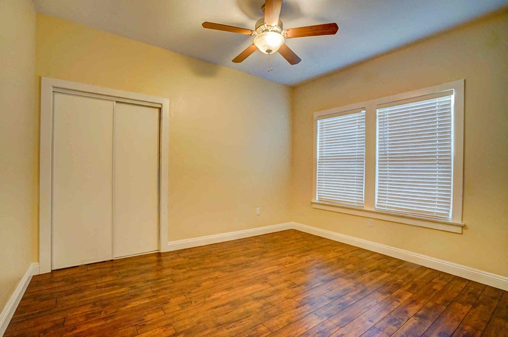 an empty living room with wood floors and a ceiling fan