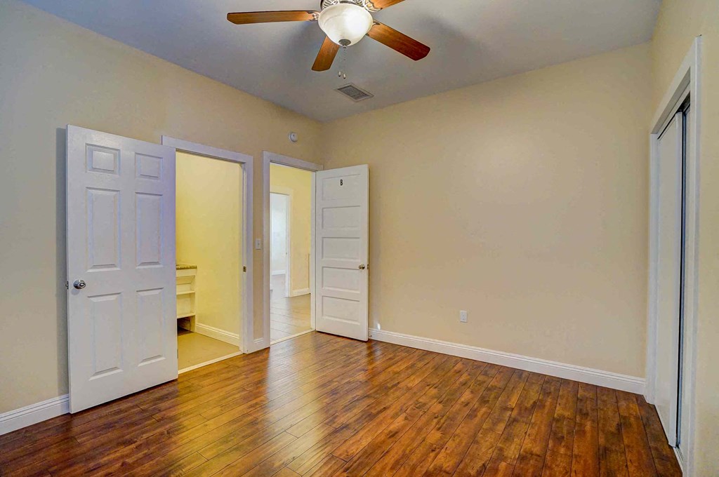 an empty living room with wooden floors and a ceiling fan
