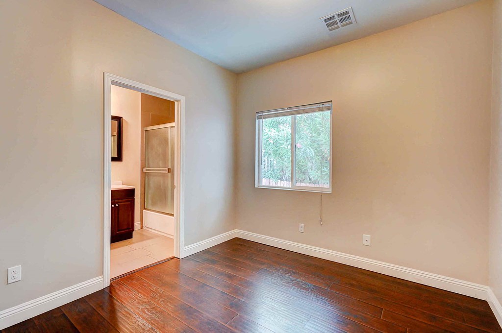 an empty living room with hard wood floors and a window