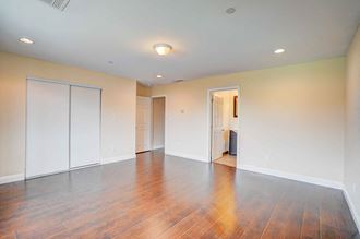 an empty living room with wood floors and white walls