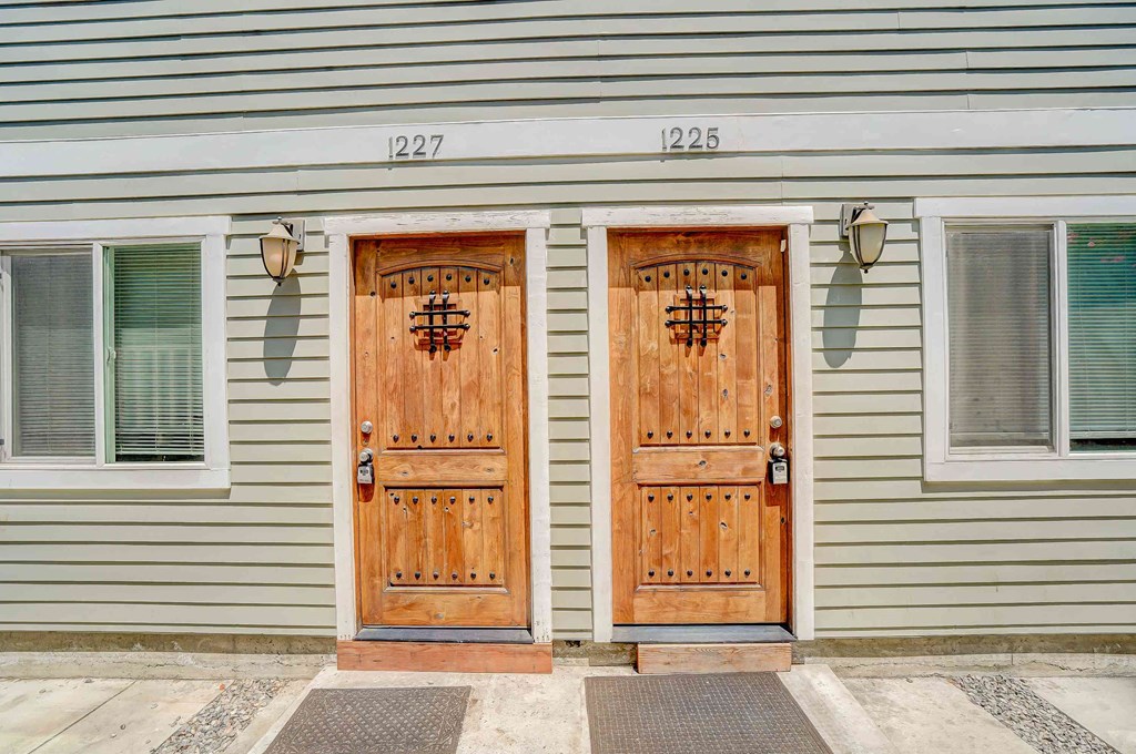 two wooden doors on the side of a house
