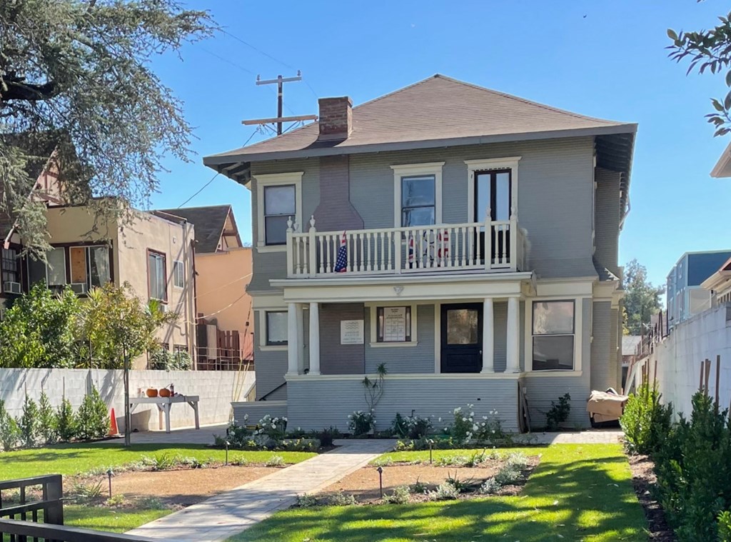 a white house with a balcony and a yard