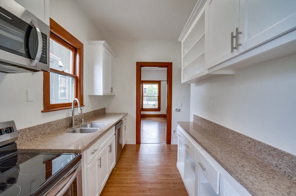 an empty kitchen with white cabinets and granite counter tops