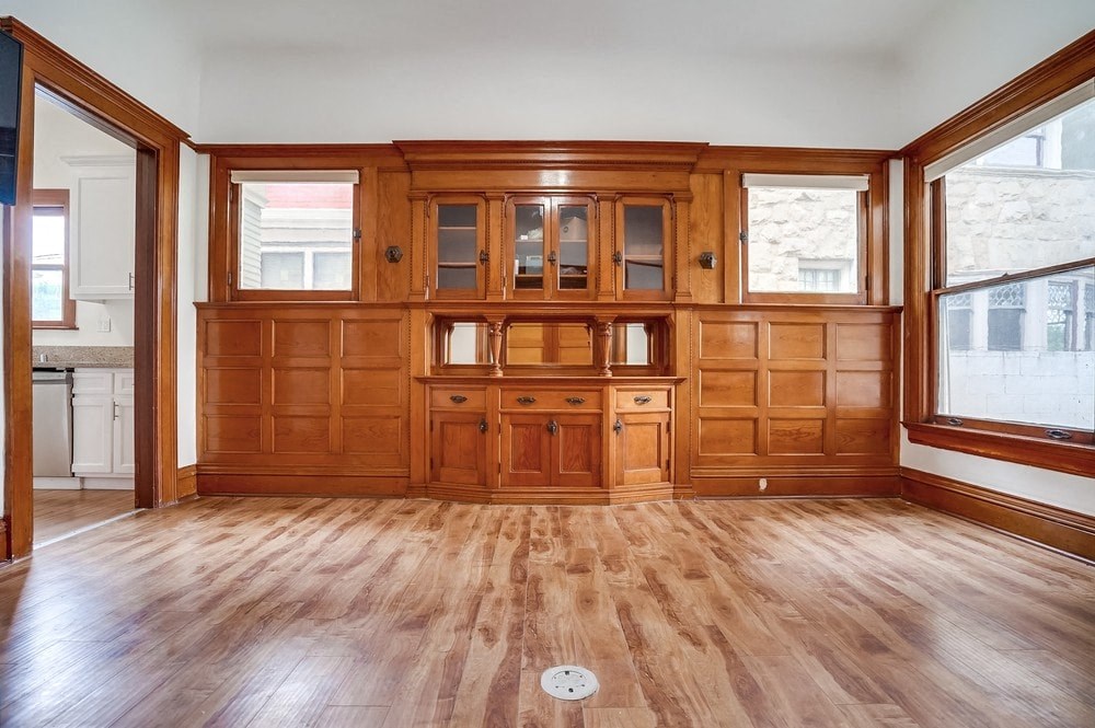 an empty living room with wood floors and wooden cabinets