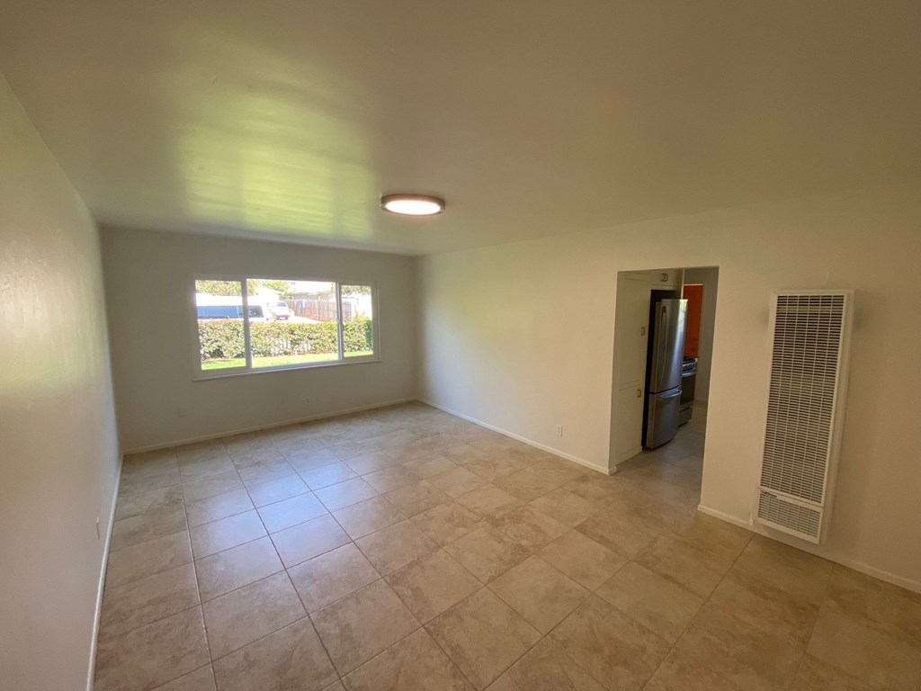 an empty living room with tile floors and a window
