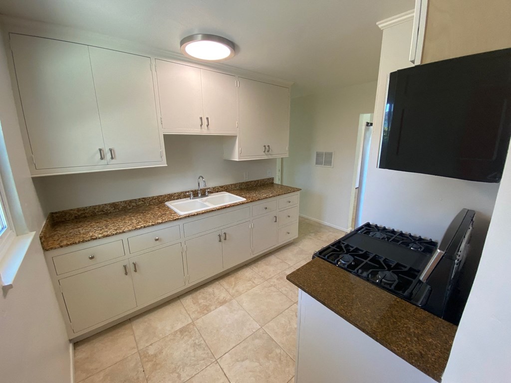 a kitchen with white cabinets and granite counter tops