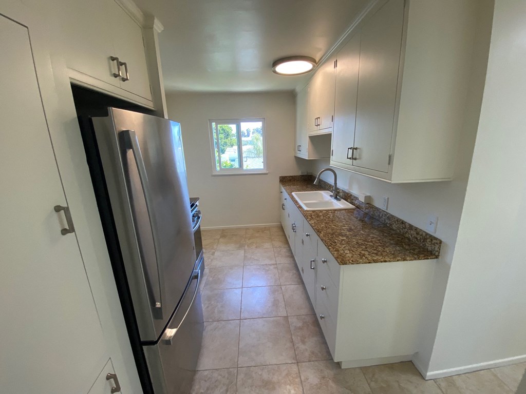 a kitchen with white cabinets and a stainless steel refrigerator