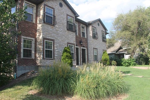 a large brick house with tall grass in front of it