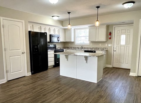 a kitchen with white cabinets and a black refrigerator