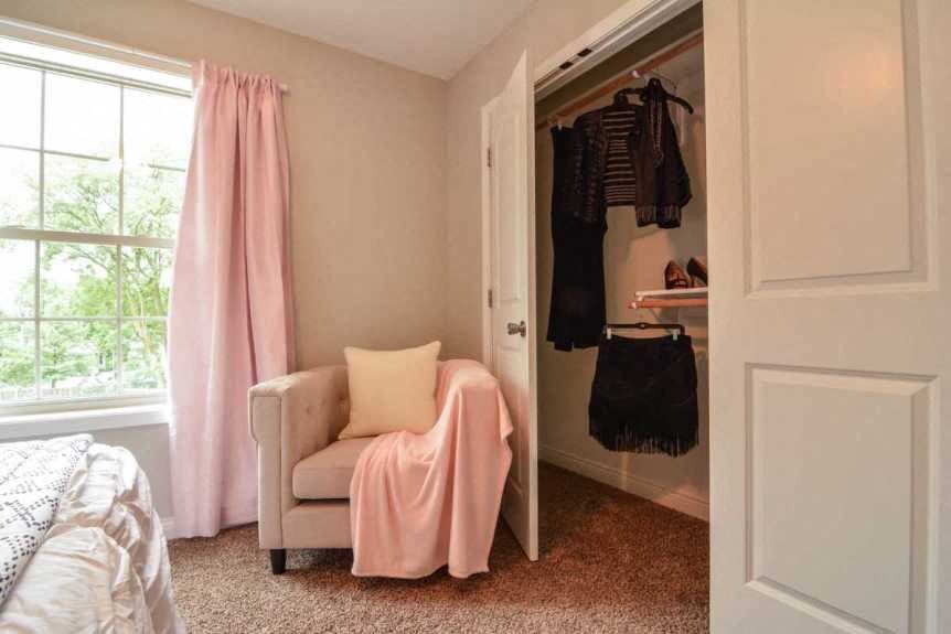 a bedroom with a bed and a closet with a chair