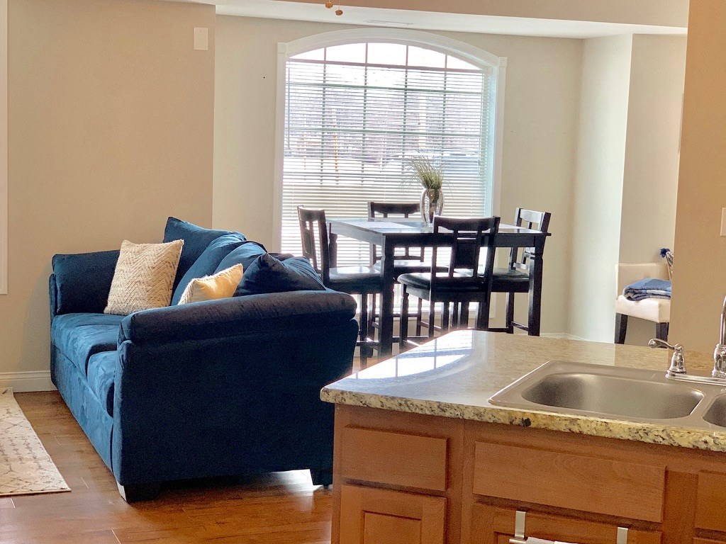 a living room with a blue couch and a kitchen with a dining room table