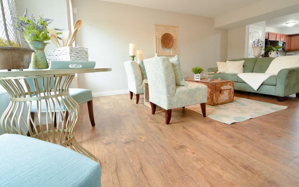 a living room with a wooden floor and a table with chairs