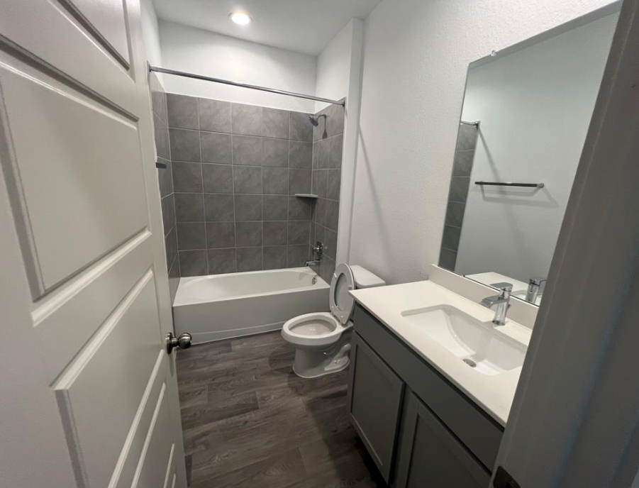A bathroom with a white sink, toilet, and a shower with a glass door.