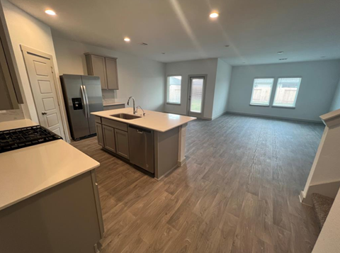 A kitchen with a refrigerator, sink, and cabinets.