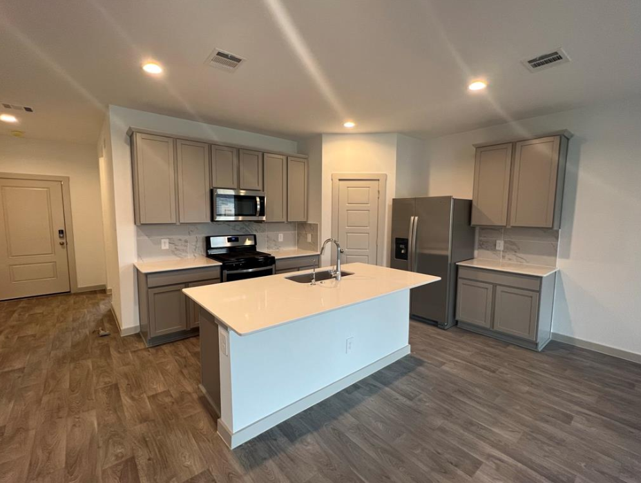 A kitchen with a white countertop and wooden flooring.