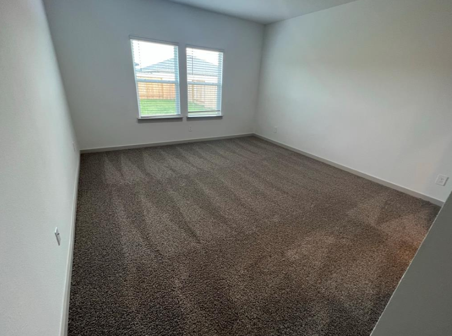 A room with a carpeted floor and a window.