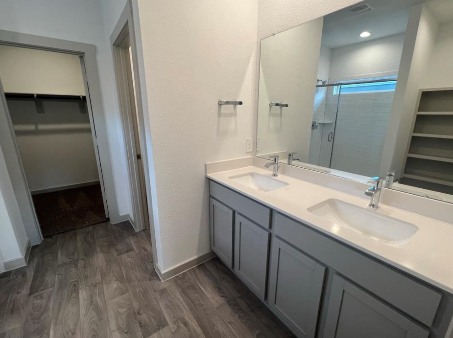A bathroom with a sink, mirror, and a shower.