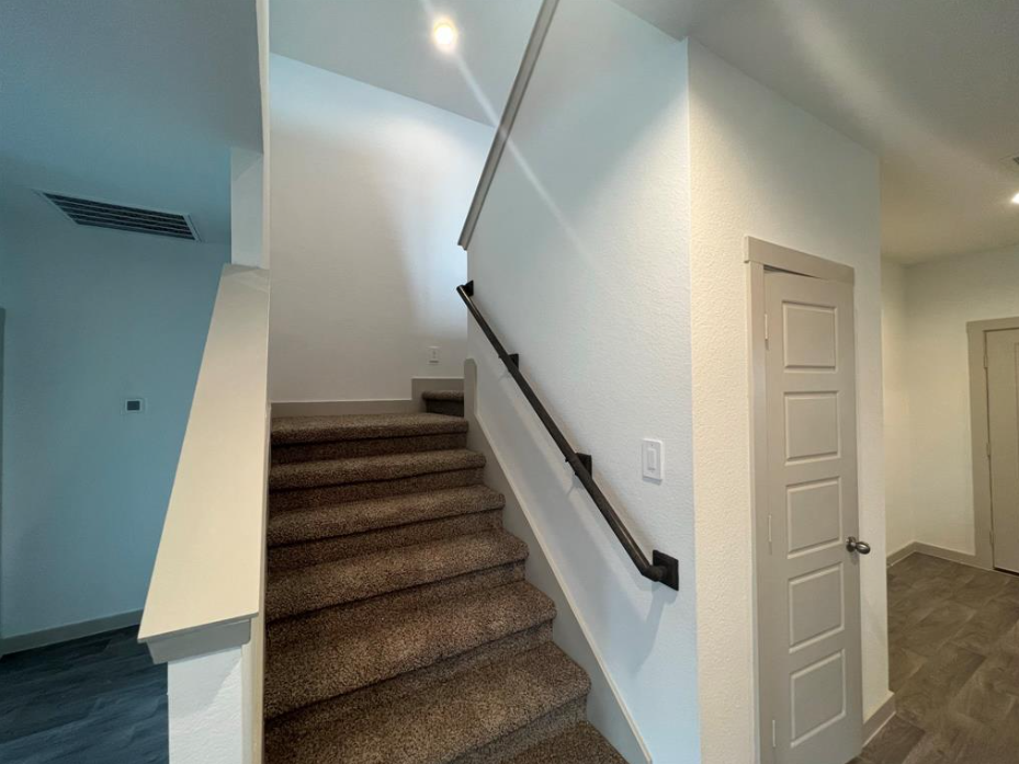 A staircase with a beige carpeted runner and black handrails.