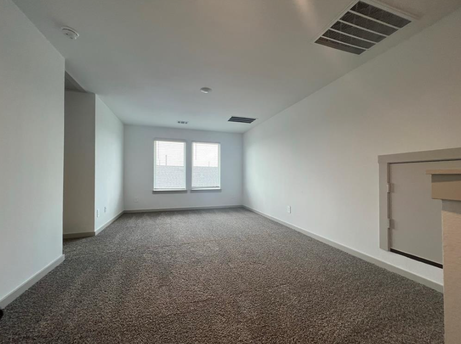 A spacious room with carpeted floor and a window with blinds.