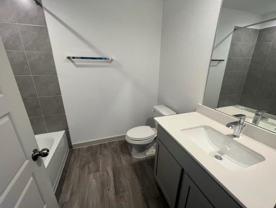 A bathroom with a toilet, sink, and mirror.