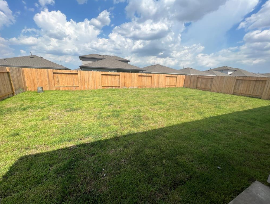 A backyard with a wooden fence and a green lawn.