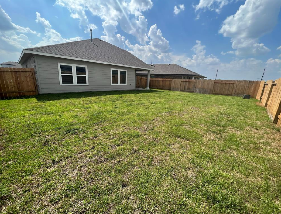 A house with a grey roof and a fence in the backyard.