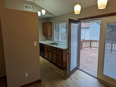 A kitchen with wooden cabinets and a sliding glass door leading to a deck.
