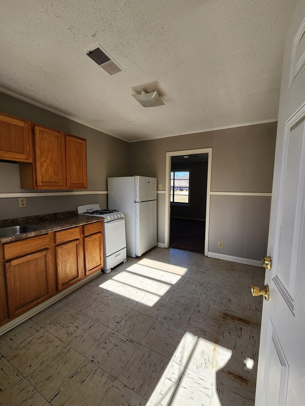 an empty kitchen with wooden floors and a white refrigerator