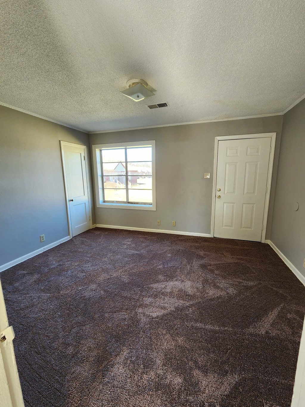 an empty living room with carpet and a window