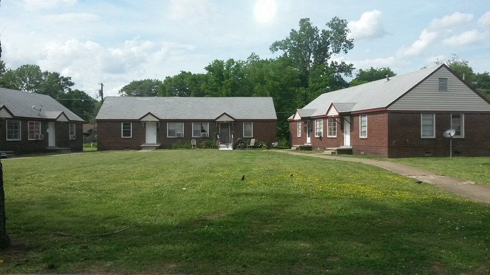 a row of houses in a grassy yard with trees in the background