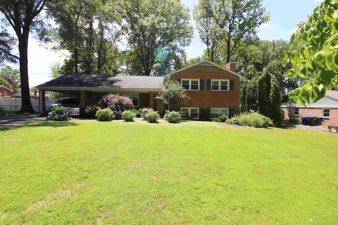 A house with a red brick exterior and a green lawn.