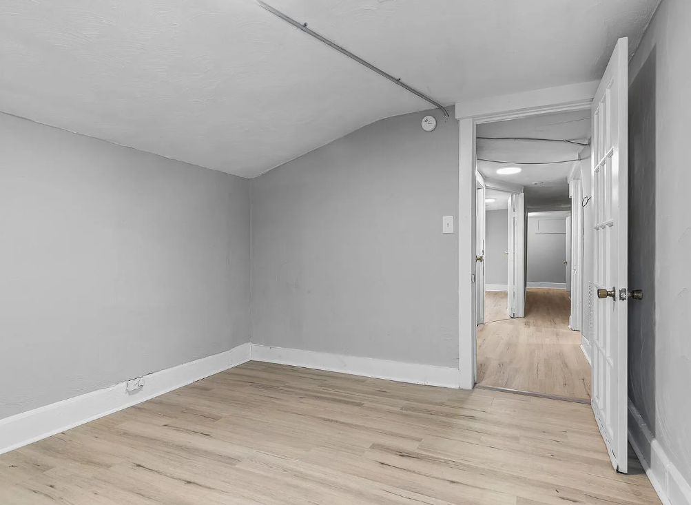 the living room and hallway of an empty house with wood floors